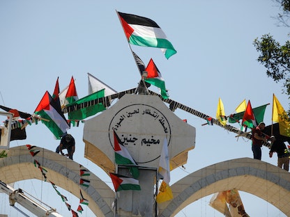 أشخاص يُعلقون الأعلام خلال زيارة الرئيس الفلسطيني محمود عباس إلى جنين في أعقاب غارة إسرائيلية. 12 يوليو 2023 - REUTERS