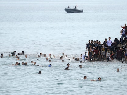 مهاجرون يسبحون وصولاً إلى السياج الفاصل بين المغرب ومدينة سبتة التي تسيطر عليها إسبانيا، 18 مايو 2021. - REUTERS