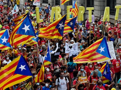 متظاهرون يلوّحون بأعلام مؤيّدة لاستقلال كاتالونيا ويرفعون كلمة "حرية" خلال مسيرة في برشلونة، 11 سبتمبر 2021 - AFP