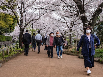  أشخاص يسيرون في متنزه بالعاصمة اليابانية طوكيو- 28 مارس 2022 - AFP
