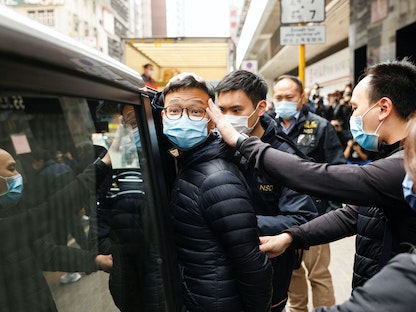 شرطة هونج كونج ترافق القائم بأعمال رئيس تحرير "ستاند نيوز" باتريك لام، وإعلاميين آخرين أثناء مغادرتهم بعد أن فتشت مكتبه، 29 ديسمبر - REUTERS