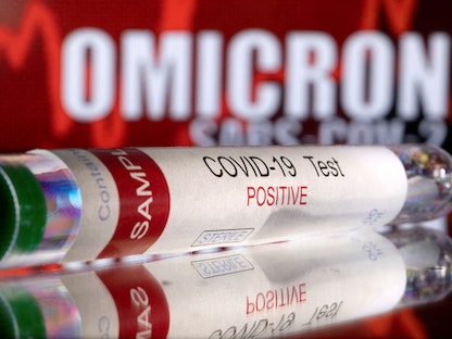 أنبوب يحمل عبارة "اختبار كوفيد-19 إيجابي" أمام الكلمات المعروضة "أوميكرون، سارس، كوف19". 11 ديسمبر 2021 - REUTERS