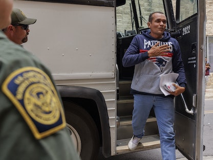 مهاجر أثناء نزوله من حافلة للسير إلى مركز للهجرة في براونزفيل بتكساس، الولايات المتحدة. 11 مايو 2023  - AFP