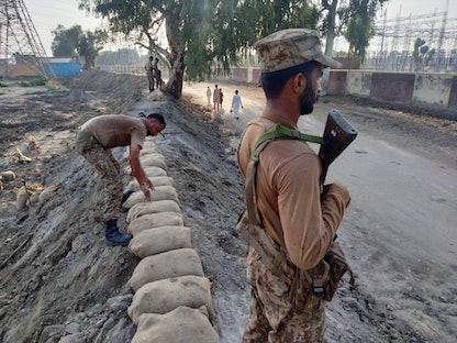 أفراد من الجيش الباكستاني يقومون بحراسة السد وتعزيز مقاومته للمياه الجارفة حماية لمحطة توليد الكهرباء، خلال موسم الرياح الموسمية في دادو، باكستان - 11 سبتمبر 2022 - REUTERS