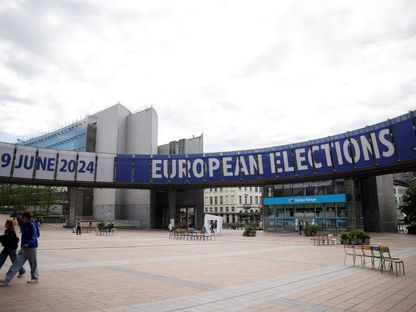 أشخاص يسيرون بالقرب من لافتة تشير إلى انتخابات البرلمان الأوروبي المقبلة في بلجيكا. 23 مايو 2024 - reuters