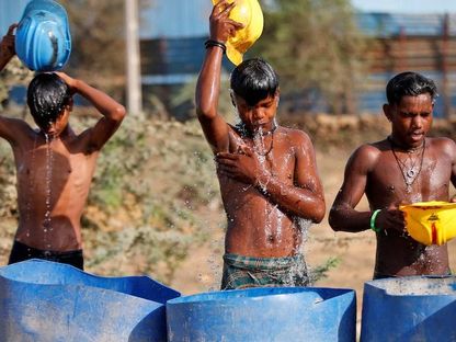 عمال يصبون الماء على أجسادهم، قرب موقع بناء في يوم حار في ضواحي أحمد آباد، الهند، 30 أبريل 2022. - Reuters