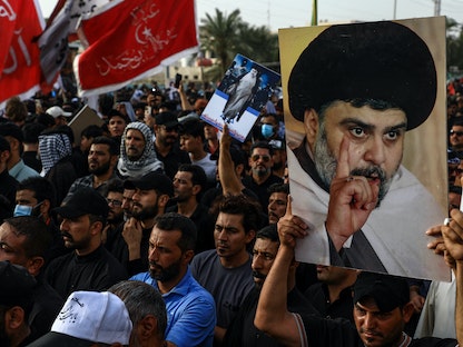 أنصار زعيم التيار الصدري مقتدى الصدر يحملون صوراً له أثناء تجمعهم في مدينة الناصرية بمحافظة ذي قار جنوبي العراق، 12 أغسطس 2022 - AFP
