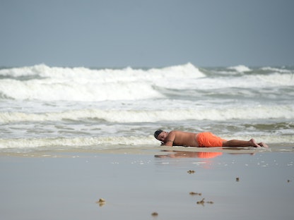 رجل يعمل على التشميس "التان" على شاطئ دايتونا في فلوريدا بالولايات المتحدة - REUTERS