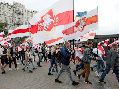  نشطاء يحملون أعلاماً تاريخية لبيلاروسيا وهم يسيرون خلال مسيرة لدعم الحركة البيلاروسية المناهضة للحكومة والمدون المعتقل رومان بروتاسيفيتش، في كييف، أوكرانيا. 30 مايو 2021 - REUTERS