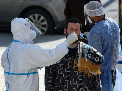 أحد أعضاء فرق التقصي الوبائي في الأردن يأخذ مسحة أنف من رجل في العاصمة عمان- 18 ديسمبر 2020 - AFP