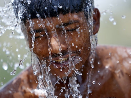 عامل يستحم من مياه مضخة في يوم صيفي حار في جورجاون، الهند. 29 مايو 2015. - REUTERS