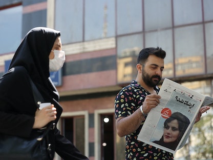 إيراني يقرأ صحيفة تحمل صورة الشابة مهسا أميني في طهران، 18 سبتمبر 2022. - REUTERS