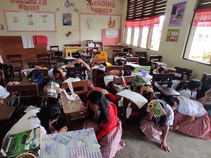طلاب مدرسة في مدينة ماتي يحتمون بعدما ضرب زلزالان قويان جنوب الفلبين- 07 مارس 2023 - AFP