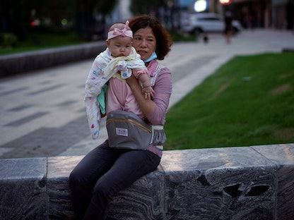 سيدة صينية تحمل طفلتها الرضيعة في مدينة ووهان خلال تفشي فيروس كورونا. 15 مايو 2020 - REUTERS