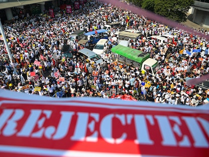 لافتة بالإنجليزية تقول "مرفوض" تعتلي حشداً من آلاف المتظاهرين ضد الانقلاب العسكري في مدينة يانغون في ميانمار، 22 فبراير 2021 - AFP