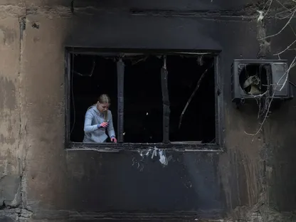 سيدة أوكرانية تزيل الزجاج المكسور من نافذة مبنى تضرر بسبب غارة روسية بطائرة مسيرة في منطقة دنيبروبتروفسك. 19 أكتوبر 2025 - رويترز