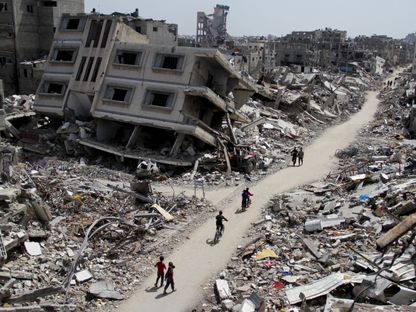 فلسطينيون يركبون دراجات عبر أنقاض المنازل والمباني التي دمرتها الحرب الإسرائيلية على غزة شمال القطاع. 31 مارس 2024 - Reuters