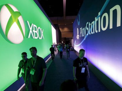 زوار يسيرون بين علامات بلايستيشن وإكس بوكس التجارية بمعرض E3 لألعاب الفيديو - REUTERS