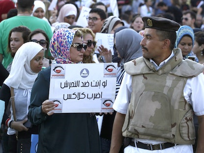 شرطي يقف أمام محتجين ضد التحرش الجنسي أمام دار الأوبرا في القاهرة - REUTERS