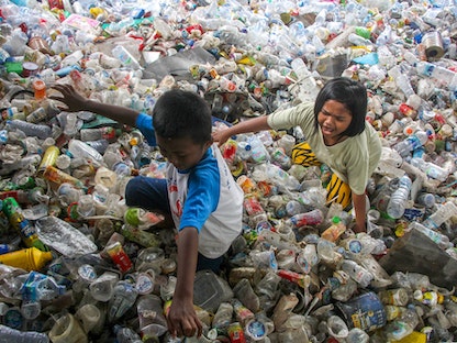 أطفال في أكوام من النفايات البلاستيكية التي تم جمعها لإعادة التدوير في ماكاسار الإندونيسية. 11 فبراير 2022 - AFP
