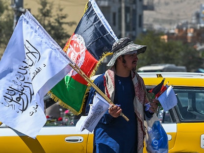 بائع يحمل أعلام أفغانستان وحركة طالبان بأحد شوارع العاصمة كابول - 8 سبتمبر 2021 - AFP