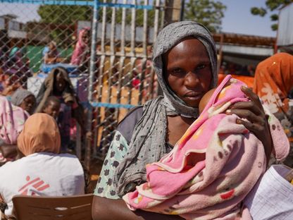 سودانية تحمل طفلها في مخيم زمزم للنازحين، الفاشر، شمال السودان. يناير 2024 - Reuters