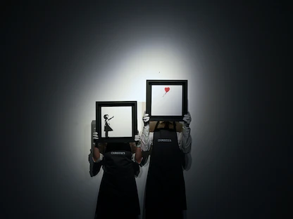 عاملان في دار "كريستيز" يحملان لوحتان لعمل الفنان البريطاني بانكسي في لندن - 1 أكتوبر 2021 - REUTERS