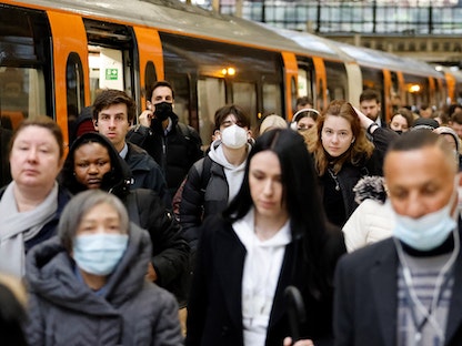 ركاب يرتدي بعضهم أقنعة واقية من فيروس كورونا يخرجون من محطة قطار في العاصمة البريطانية لندن. 1 مارس 2022 - AFP