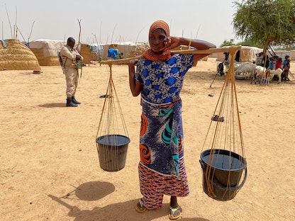 امرأة تحمل الماء في مخيم للنازحين في بلدة أولام بالنيجر. 6 يوليو 2021 - REUTERS