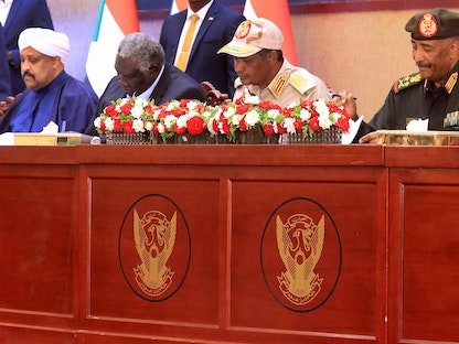 قائد الجيش السوداني عبد الفتاح البرهان وقائد قوات الدعم السريع محمد حمدان دقلو (الثاني إلى اليمين) إلى جانب القادة المدنيين خلال التوقيع على "الاتفاق الإطاري" بهدف إنهاء الأزمة السياسية، الخرطوم. 5 ديسمبر 2022 - AFP