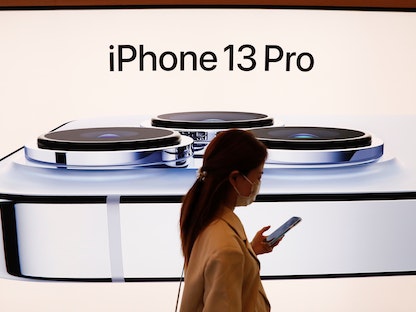 امرأة تمر أمام صورة لجهاز iPhone 13 Pro في متجر Apple ببكين -الصين- 24 سبتمبر 2021 - REUTERS