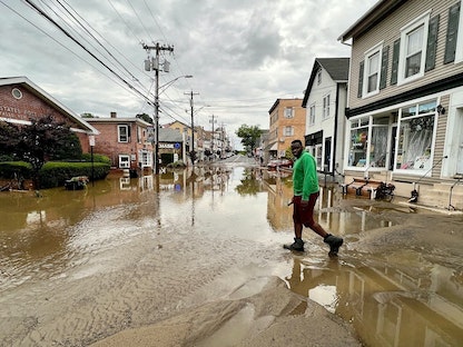 شخص يسير عبر طريق غمرته المياه جراء الأعاصير في مدينة نيويورك الأميركية. 9 يوليو 2023 - REUTERS