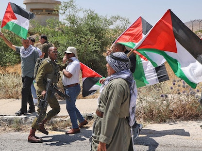 متظاهرون فلسطينيون يلوحون بالعلم الوطني في مدينة طوباس خلال تجمع للتنديد بالتوسع الاستيطاني الإسرائيلي في غور الأردن -  6 حزيران 2022 - AFP
