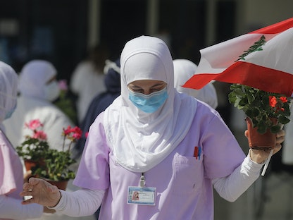 ممرضة تتسلم الزهور بمناسبة اليوم العالمي للتمريض في مستشفى رفيق الحريري الجامعي بالعاصمة بيروت، 12 مايو 2020 - AFP
