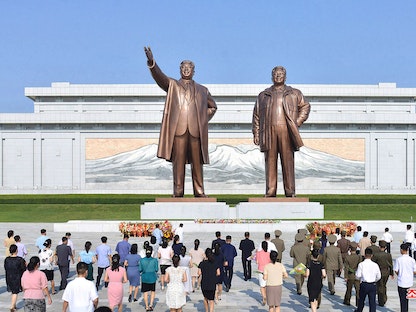 يقدمون الزهور لتمثالي الرئيس السابق كيم إيل سونغ والرئيس السابق كيم جونغ إيل، في مانسوداي في بيونغ يانغ، للاحتفال بالذكرى الـ 68 لانتهاء الحرب الكورية. 27 يوليو 2021 - AFP