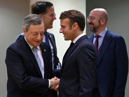 الرئيس الفرنسي إيمانويل ماكرون يصافح رئيس الوزراء الإيطالي السابق ماريو دراجي خلال اجتماع لقادة الاتحاد الأوروبي في بروكسل. 21 أكتوبر 2022 - AFP