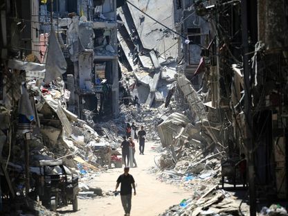 فلسطينيون في أحد شوارع خان يونس بينما تبدو آثار الدمار الذي أحدثته الغارات الإسرائيلية المتواصلة على قطاع غزة. 11 يونيو 2024 - AFP