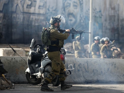 جندي إسرائيلي يصوب سلاحه تجاه فلسطينيين في الضفة الغربية المحتلة- 27 ديسمبر 2022 - REUTERS
