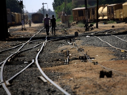 سودانيون يسيرون على امتداد خطوط السكك الحديدية في محطة سكة حديد عطبرة-أرشيفية - REUTERS