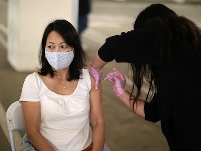 امرأة ترتدي كمامة بينما تتلقى لقاحاً مضاداً لفيروس كورونا في مدينة لوس أنجلوس بولاية كاليفورنيا الأميركية - REUTERS