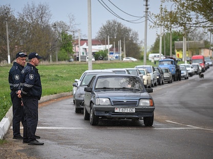 شرطيان من مولدوفا أمام طابور لسيارات تستعد لدخول إقليم ترانسنيستريا - 28 أبريل 2022 - AFP