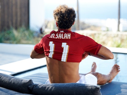 محمد صلاح يرتدي قميص ليفربول خلال الإعلان عن تجديد تعاقده مع الفريق الإنجليزي - twitter/MoSalah