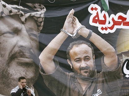 أحد أنصار حركة فتح الفلسطينية أمام ملصق للأسير مروان البرغوثي خلال مسيرة في الخليل. 20 مارس 2007 - REUTERS