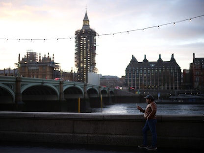 رجل يتصفح هاتفه الذكي قبالة مبنى البرلمان البريطاني في العاصمة لندن - REUTERS