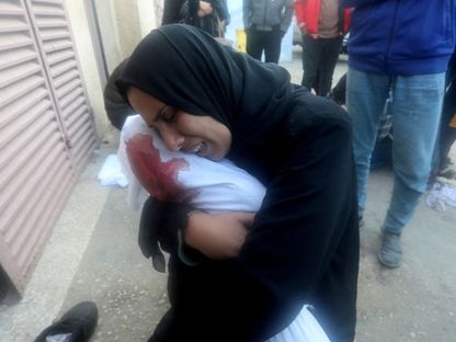 امرأة فلسطينية تحمل جثة طفل قتلته إسرائيل في غارات على دير البلح وسط قطاع غزة. 20 مارس 2024 - Reuters