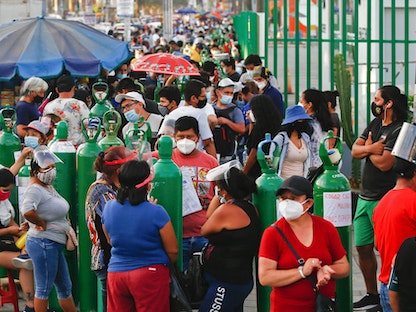 أشخاص ينتظرون إعادة ملء اسطوانات الأكسجين خارج مصنع بمدينة ليما في بيرو- 19 فبراير 2021 - AFP