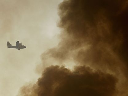 طائرة إطفاء وسط أعمدة الدخان أثناء مشاركتها في عمليات إخماد حرائق غربي أثينا في اليونان. 20 يوليو 2023 - REUTERS