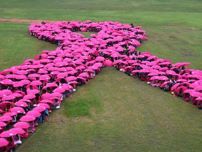 طلاب جامعيون يحملون مظلات لتشكيل شريط وردي خلال حملة توعية بسرطان الثدي في الهند. 31 أكتوبر  2022 - AFP