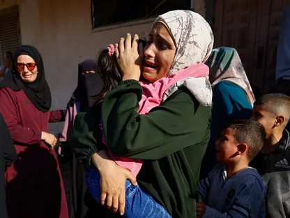 سيدة فلسطينية تحمل طفلاً في مستشفى شهداء الأقصى بوسط قطاع غزة خلال جنازة فلسطينيين قتلتهم غارة إسرائيلية. 19 أكتوبر 2025 - REUTERS