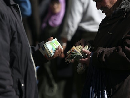 فلسطينيان يتبادلان الأموال في رام الله بالضفة الغربية - REUTERS